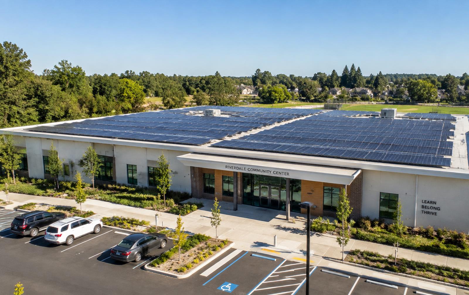 A community center with its flat roof fully covered by a commercial solar array